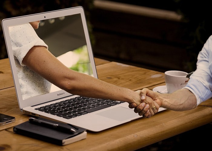 graphic illustration depicting two people handshaking through online transaction